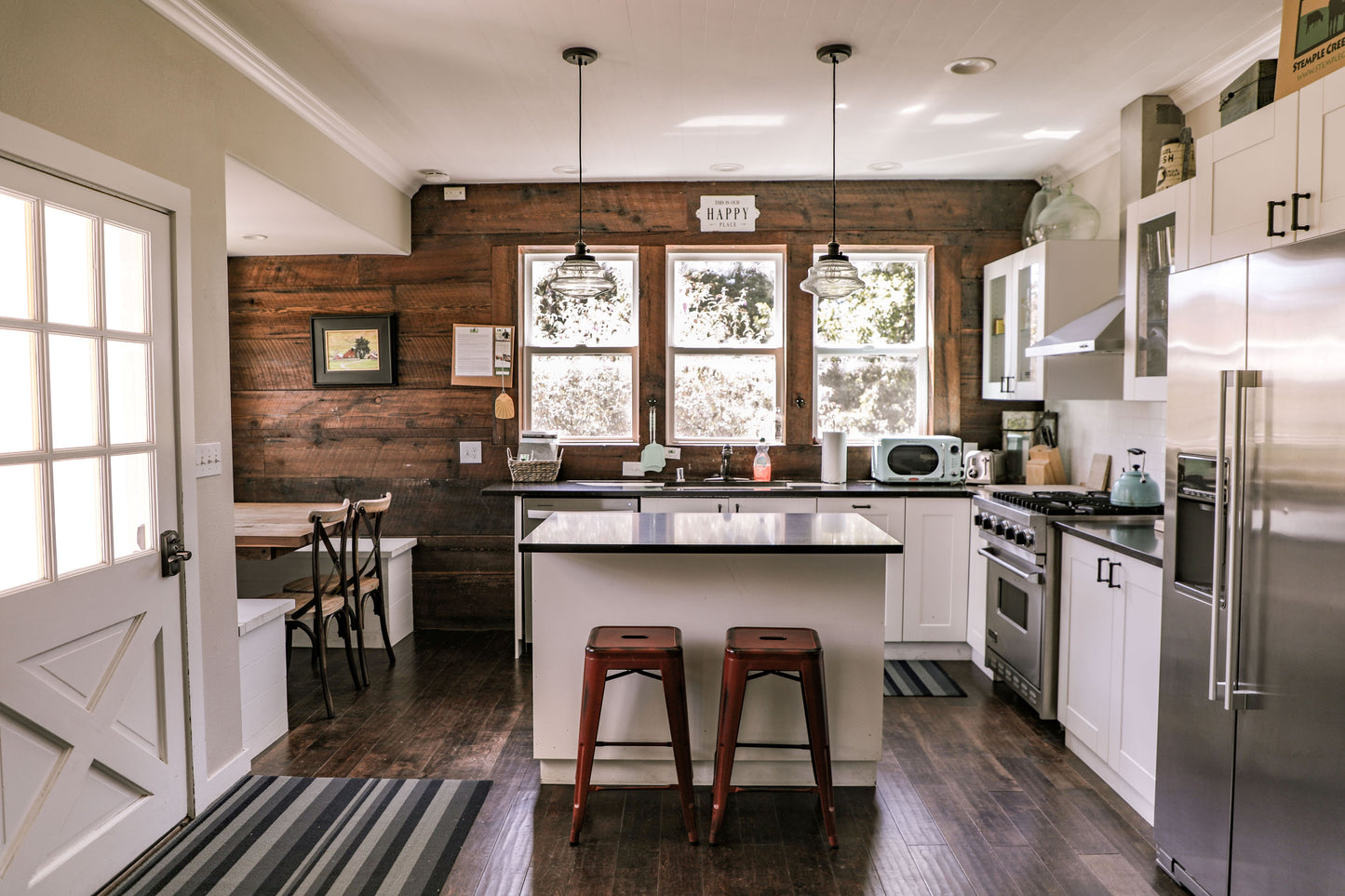 The kitchen has a Viking gas range, Keurig coffee maker, pots and pans, a microvave, counter seating at the island, and a dining table. There is a gas grill outside.