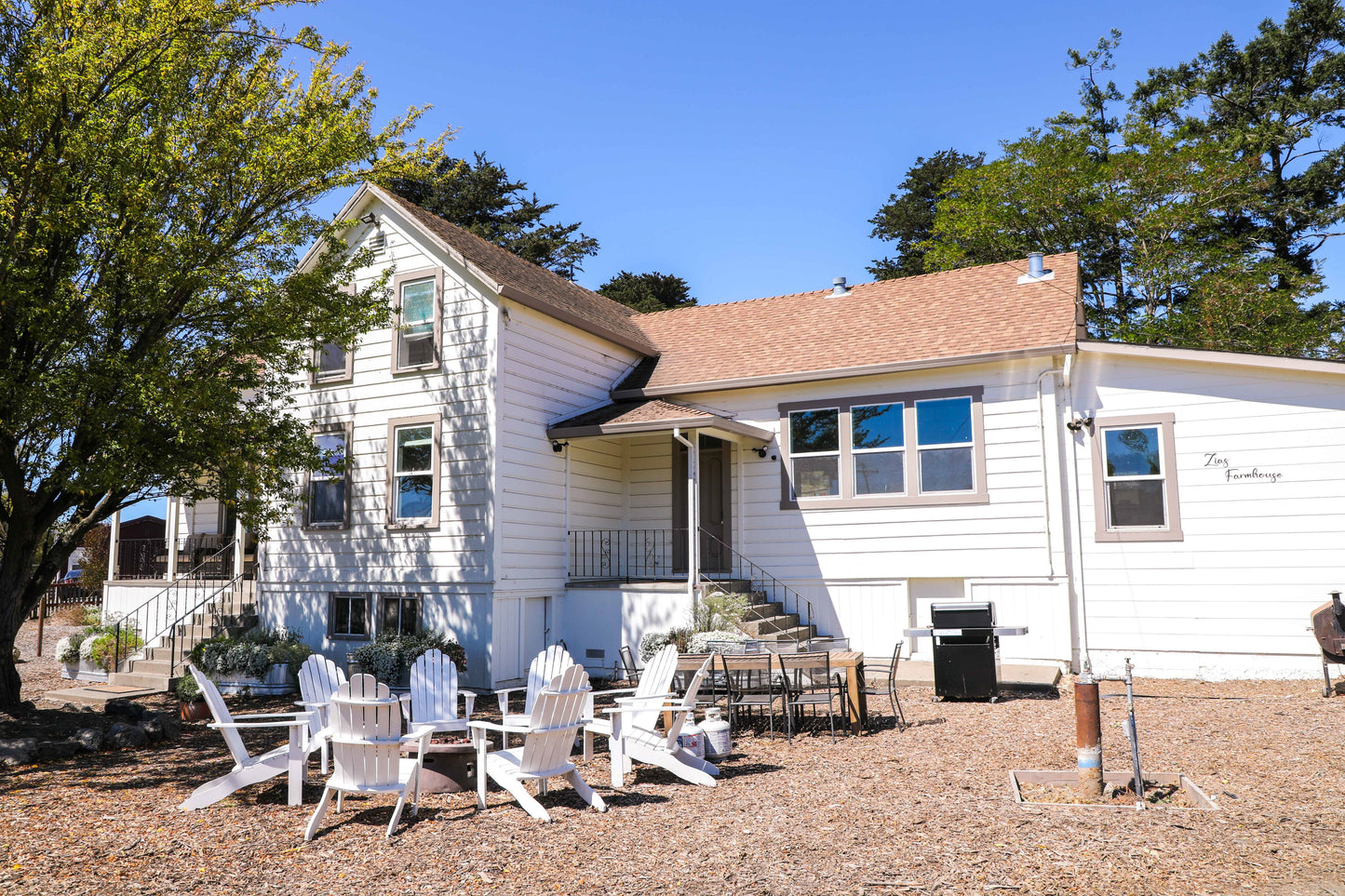 The front yard has a gas firepit, adirondack chairs, an outdoor dining table, and a gas BBQ.