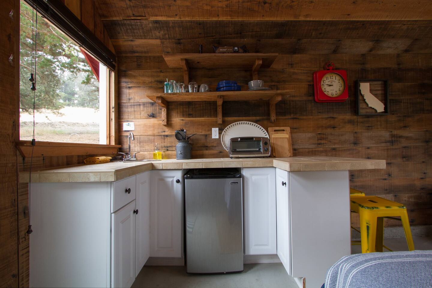 The kitchenette has a toaster oven, hot plate, kettle, Keurig cofee maker, small sink, and dorm sized refigerator. There is a gas grill outside.