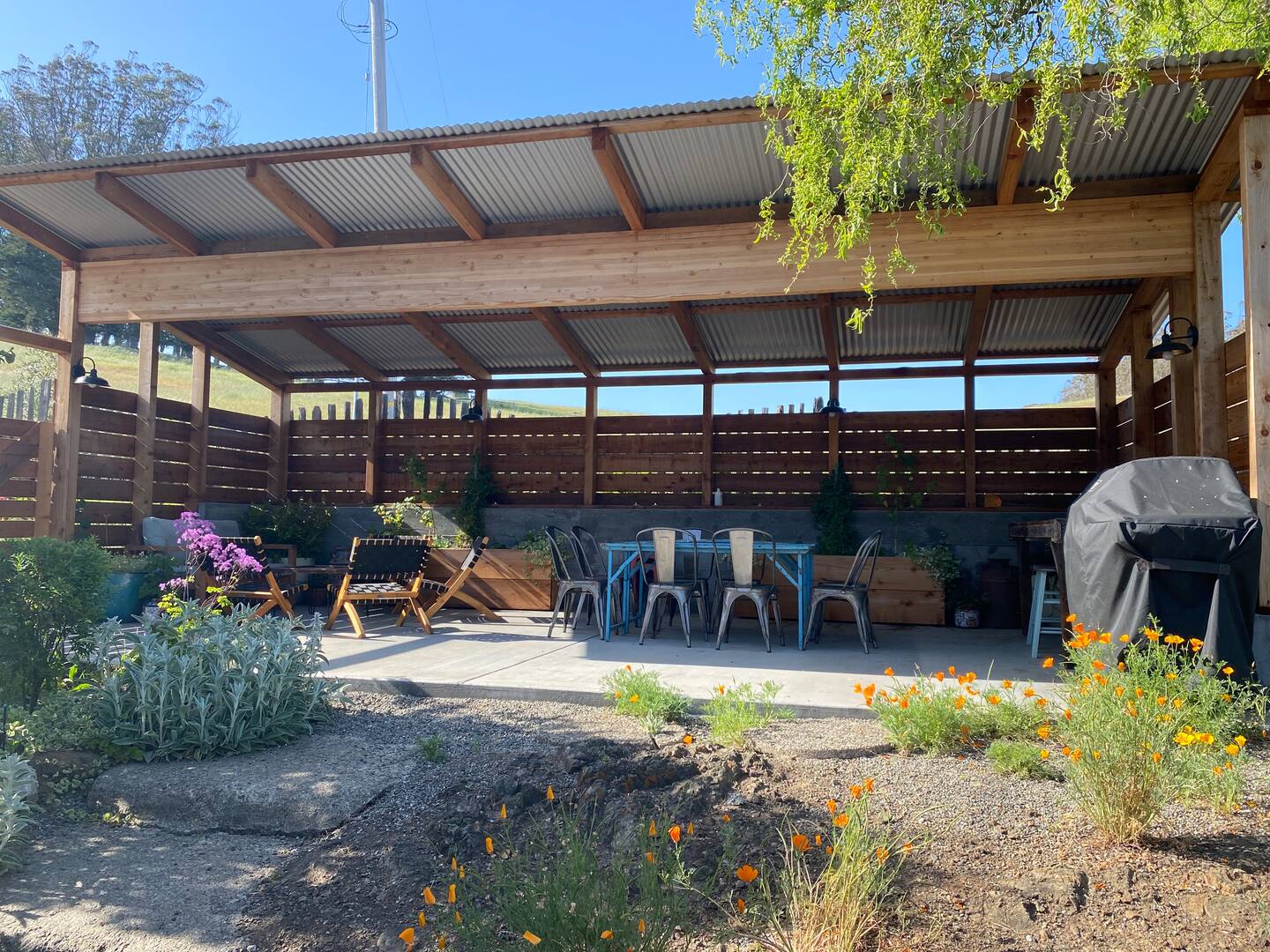 Covered patio has a seating area, dining table, and gas BBQ.