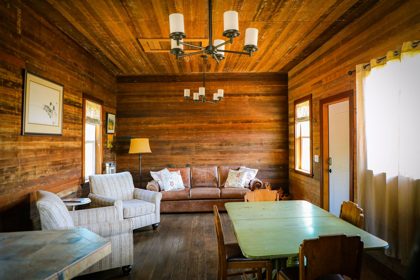 The Cabin's main room has reading chairs, a leather couch that has a comfotable queen-sized pull-out bed, and a dining table. 