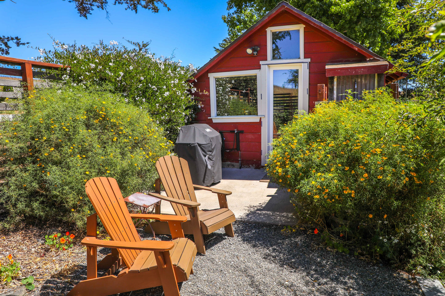 Backyard has chairs, a gas grill, and an outdoor shower. 