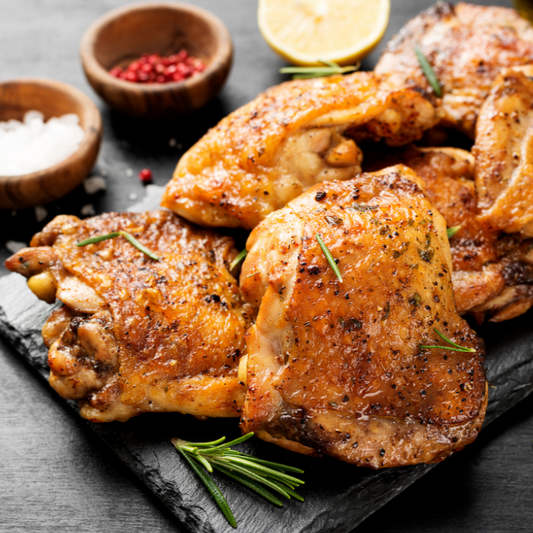 Roasted chicken thighs on a slate board with herbs and spices